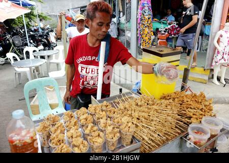Taytay, Rizal, Philippines - 20 février 2020: Le vendeur de nourriture de rue vend de la peau de poulet croustillante et de l'intestin frits à son panier alimentaire. Banque D'Images