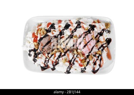 Dessert de la crème glacée vanille, crème fouettée, noix, chocolat et garniture de baies, fond séparé et blanc isolé sur la plaque carrée. Plat pour le menu Banque D'Images