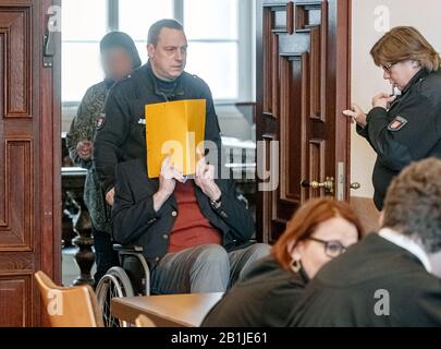 Hambourg, Allemagne. 26 février 2020. Le défendeur cache son visage derrière une couverture de dossier lorsqu'il est poussé dans la salle d'audience dans un fauteuil roulant. Selon le ministère public, il était en service en tant que jeune homme dans le camp de concentration de Stutthof près de Danzig d'août 1944 à avril 1945. L'affaire sera entendue devant le tribunal pour mineurs. (Az. 617 Ks 10/19 Pichet.) Crédit: Markus Scholz/Dpa/Alay Live News Banque D'Images