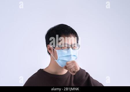 Le jeune homme asiatique crasse, se sentant mal, vomit malade avec un masque médical bleu isolé sur fond blanc, gros plan, espace de copie. Banque D'Images