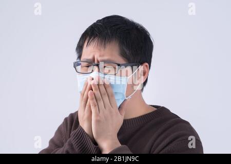 Le jeune homme asiatique crasse, se sentant mal, vomit malade avec un masque médical bleu isolé sur fond blanc, gros plan, espace de copie. Banque D'Images