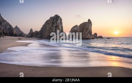 Portugal Ursa Beach sur la côte de l'océan Atlantique. La pile de la mer est rocheuse au coucher du soleil. Vagues foamy qui s'étendent jusqu'à la côte de sable. Paysage pittoresque vacances Banque D'Images