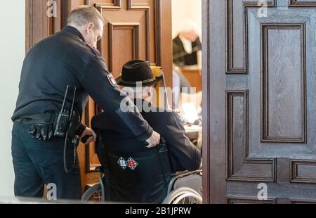 Hambourg, Allemagne. 26 février 2020. Le défendeur cache son visage derrière une couverture de dossier lorsqu'il est sorti de la salle d'audience dans un fauteuil roulant pendant une pause dans la procédure. Selon le ministère public, il était en service en tant que jeune homme dans le camp de concentration de Stutthof près de Danzig d'août 1944 à avril 1945. L'affaire sera entendue devant le tribunal pour mineurs. (Az. 617 Ks 10/19 Pichet.) Crédit: Markus Scholz/Dpa/Alay Live News Banque D'Images