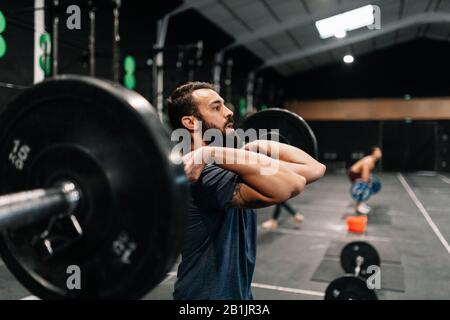 Jeune haltérophile masculin exerçant dans la salle de gym Banque D'Images