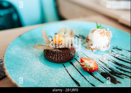 Fondue au chocolat à la pâtisserie au dessert avec une demi-fraise fraîche et une boule de crème glacée avec des noix de pin. Magnifique dessert servi dans un café sur le porce bleu Banque D'Images
