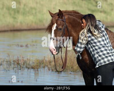 Une belle jeune fille et son cheval se tiennent dans le paysage sur la côte du Suffolk. Banque D'Images