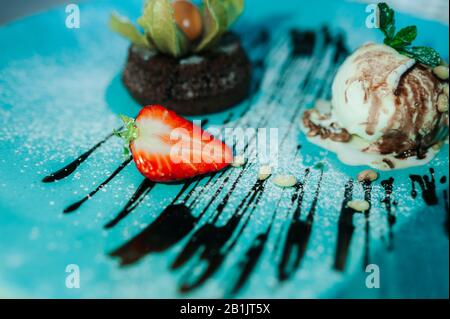 Fondue au chocolat à la pâtisserie au dessert avec une demi-fraise fraîche et une boule de crème glacée avec des noix de pin. Magnifique dessert servi dans un café sur le porce bleu Banque D'Images