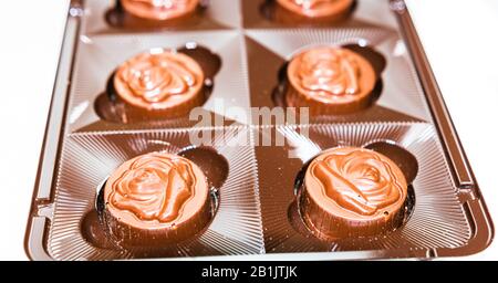 Variété de délicieux pralines de chocolat dans la boîte. Gros plan des bonbons isolés sur la mise au point sélective blanche. Banque D'Images