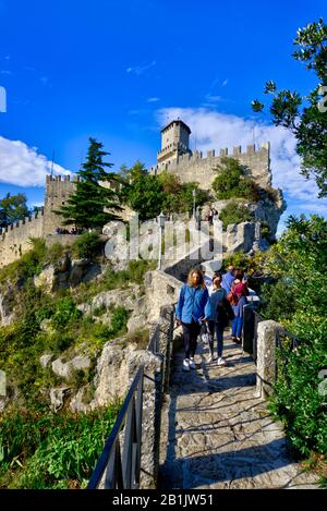 Saint-Marin, Saint-Marin - 19 octobre 2019: Ligne de touristes descendant le long du chemin de pierre avec la tour Guaita en arrière-plan. Banque D'Images