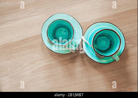 Deux très belles tasses vides de couleur bleue et menthe avec soucoupes sur une table en bois rugueuse. Vue sur le dessus sur un dîner romantique intime pour deux personnes Banque D'Images