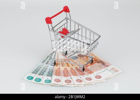 Mini panier sur pile de billets roubles sur fond gris, argent ou concept de monnaie Banque D'Images