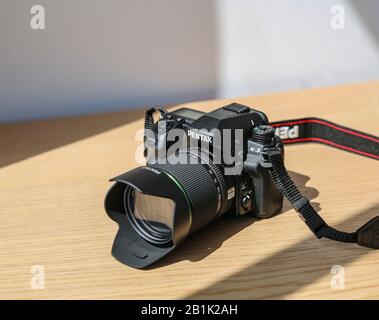 Boîtier pour appareil photo reflex numérique étanche Pentax K 3 avec kit d'objectif 18-135 mm sur table en bois sous la lumière du soleil Banque D'Images