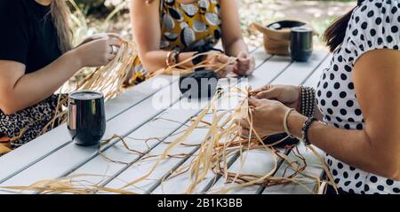 Les femelles tissent des paniers sur l'atelier d'artisanat. Mains tenant l'artisanat, gros plan. Banque D'Images