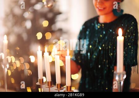 Femme imreconnaissable souriant et enflammant des bougies tout en créant une ambiance romantique en soirée à la maison Banque D'Images