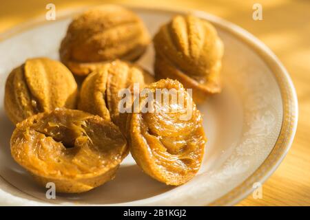 Petits cookies sous forme de noix sur une soucoupe blanche. Bonbons sur la table ensoleillée. Banque D'Images