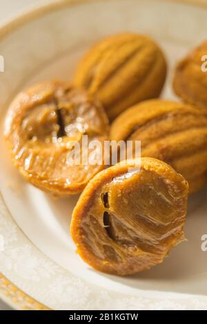 Biscuits en noyer avec lait condensé dans la soucoupe blanche. Un ouvert dans la moitié. Bonbons sur la table ensoleillée. Banque D'Images