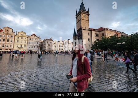 Un homme avec un sac à dos et un sweat à capuche rouge regarde par surprise la place centrale de la ville de Prague. L'idée et le concept de découvertes et de voyages Banque D'Images
