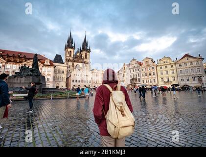 Un homme avec un sac à dos et un sweat à capuche rouge regarde par surprise la place centrale de la ville de Prague. L'idée et le concept de découvertes et de voyages Banque D'Images
