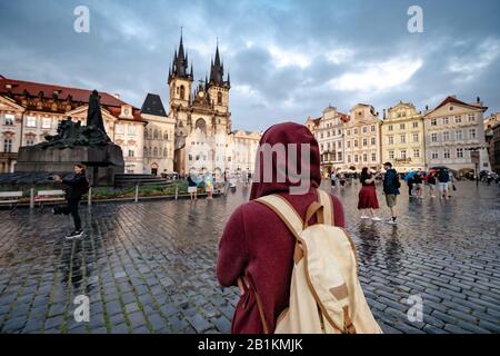Un homme avec un sac à dos et un sweat à capuche rouge regarde par surprise la place centrale de la ville de Prague. L'idée et le concept de découvertes et de voyages Banque D'Images
