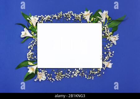 Feuille carrée vierge de papier avec composition en fleurs blanches sur fond bleu. Bonne fête des mères, printemps, concept de pâques. Banque D'Images