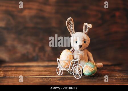 Oeufs de couleur dans la glace de Pâques, lapin assis près de la bicyclette Banque D'Images