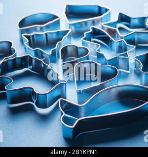 Moules métalliques pour cookies sur fond bleu. Moules à pâtisserie en forme de fête pour la fabrication de desserts décorés. Avec rétroéclairage à contraste lumineux. Banque D'Images