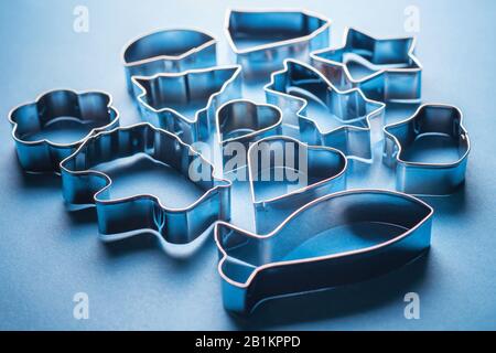 Moules métalliques pour cookies sur fond bleu. Moules à pâtisserie en forme de fête pour la fabrication de desserts décorés. Avec rétroéclairage à contraste lumineux. Banque D'Images