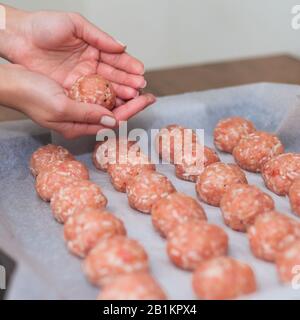 Les mains féminines font des boulettes de viande dans le four. Boulettes de viande brutes suédoises. Viandes de bœuf frites maison. Cuit sur parchemin Banque D'Images