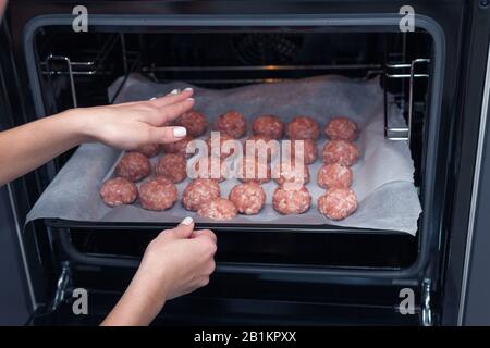 Les mains féminines font des boulettes de viande dans le four. Boulettes de viande brutes suédoises. Viandes de bœuf frites maison. Cuit sur parchemin Banque D'Images