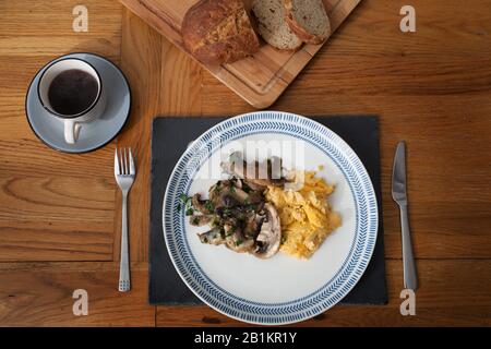Petit-déjeuner composé d'œufs brouillés, de champignons cuits à l'ail et à la coriandre, de pain frais et de café noir Banque D'Images
