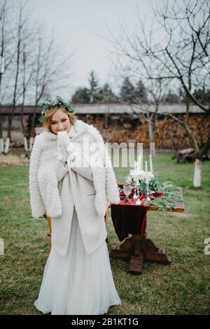 La mariée se tient sur la pelouse près de la table de banquet habillée en veste. Banque D'Images