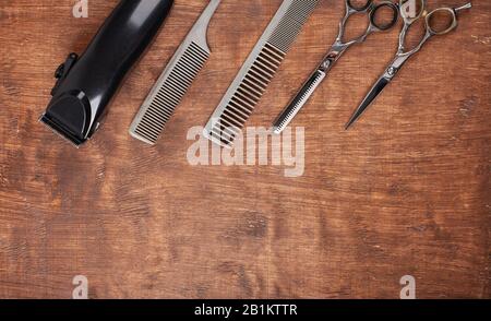 Outils de coupe dans les coupes de coiffure sur un fond sombre. Un rasoir dangereux, une machine à écrire, une tondeuse à cheveux. Banque D'Images