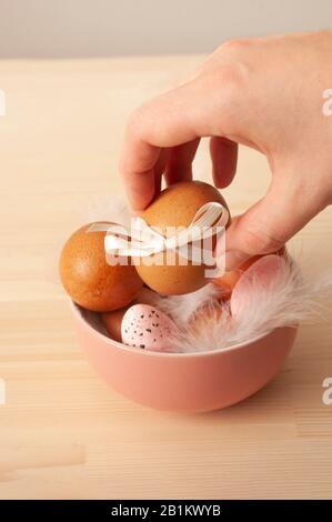 œufs de poulet, œufs de caille dans un bol rose, cuisine de pâques, traditionnelle, catholique, vacances orthodoxes. Pâques 2020.Main tenant l'oeuf Banque D'Images