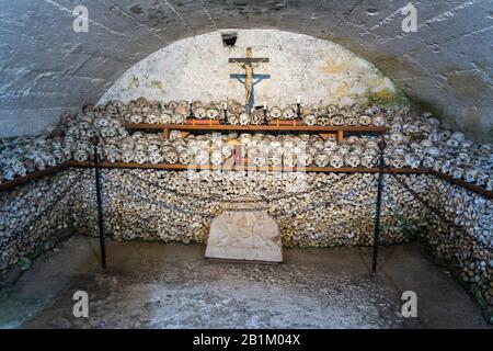 Hallstatt, Autriche – 9 Juillet 2016. Vue intérieure de la maison de charme Beinhaus dans la chapelle St Michael de Hallstatt, avec des rangées de crânes empilés. Un petit cha Banque D'Images