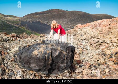 Une touriste féminine examine une grande bombe volcanique de lave basaltique vésiculaire issue de l'éruption explosive de 1971 du volcan Teneguia, la Palma, îles Canaries Banque D'Images