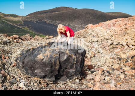 Une touriste féminine examine une grande bombe volcanique de lave basaltique vésiculaire issue de l'éruption explosive de 1971 du volcan Teneguia, la Palma, îles Canaries Banque D'Images