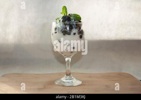 Tasse de sueur froide contenant des bleuets naturels de yaourt blanc et des feuilles de menthe fraîche sur plateau en bois dessert gastronomique sans sucre à Mexico Banque D'Images