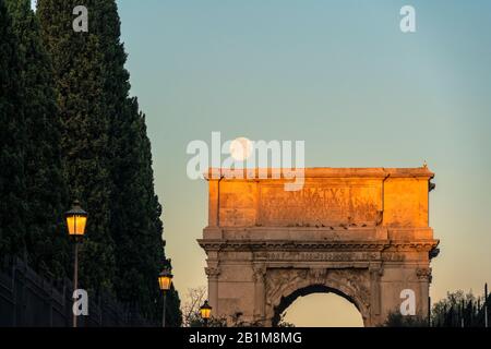 Pleine lune au lever du soleil sur l'arche triomphale d'Arco di Tito, la Fora impériale, Rome, Lazio, Italie Banque D'Images