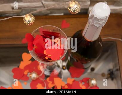 Cœur en papier rouge à l'intérieur de la vitre avec bouteille de champagne sur fond de structure en pierre avec lumière. Signe d'amour pour la Saint-Valentin ou le mariage. Banque D'Images