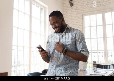 Jeune employé de bureau africain avec smartphone sur le lieu de travail Banque D'Images