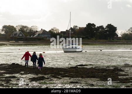 Jeunes enfants / enfants / enfants / enfants filles de 5, 7 et 9 ans marcher sur les vasières / marcher sur des vasières à marée basse quand la mer est sortie et il y a un danger de sable rapide près de Bosham Quay, Chichester dans le West Sussex. ROYAUME-UNI (114) Banque D'Images