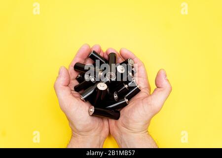 Pile de piles AA noires dans la poignée de mans sur fond jaune. Banque D'Images