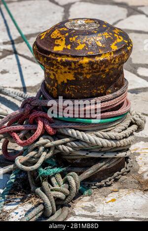 Un bateau-bateau sur un quai ou un mur de port avec des cordes multicolores sur un cabestan pour l'expédition et les bateaux. Banque D'Images