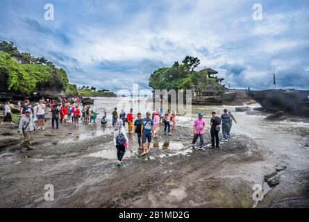 Visiteurs et pèlerins à Tanah Lot, une formation de roches au large de l'île indonésienne de Bali, qui abrite un ancien temple de pèlerinage hindou Pura Tanah Lot, Bal Banque D'Images