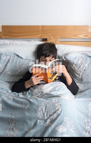 Young Boy lit le livre de Harry Potter dans le lit,.UK Banque D'Images