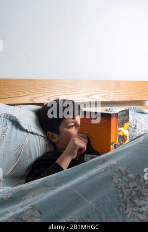 Young Boy lit le livre de Harry Potter dans le lit,.UK Banque D'Images