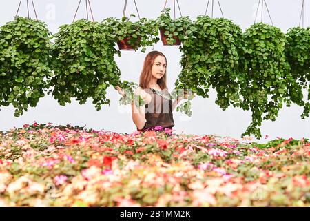 jeune femme vêtue de fleurs et de plantes ampélées décoratives sur fond clair Banque D'Images