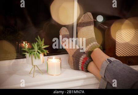 Vue arrière d'une femme non reconnaissable dans des vêtements chauds se relaxant dans une chambre confortable le soir à la maison. Gros plan Banque D'Images