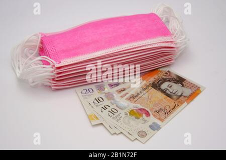Masques roses pour la protection contre les virus et billet de billet de livre sterling. Concept de prix élevé des masques chirurgicaux pendant l'épidémie en Europe et au Royaume-Uni. Banque D'Images