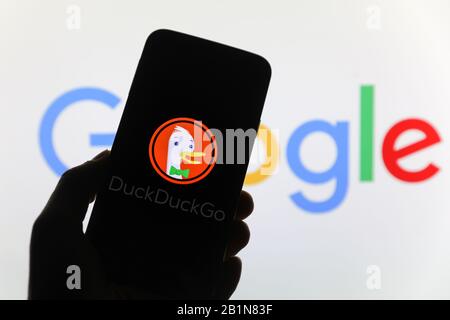 Duck Duck Go Web Search Engine logo de la société vu sur l'écran de smartphone avec le logo Google visible flou en arrière-plan Banque D'Images